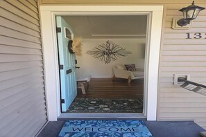 A front door with a 'WELCOME' mat, a wall-mounted light fixture, and a number '13' sign. -  Welcome to Lago Amore / Spacious 4 Bedroom 2 bath Retreat 1 mile to downtown (Coeur d'Alene)