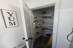 A pantry with shelves stocked with food items and a 'YUM' sign on the wall. -  Welcome to Lago Amore / Spacious 4 Bedroom 2 bath Retreat 1 mile to downtown (Coeur d'Alene)