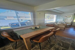 A dining area with a wooden table, leather chairs, and a view through large windows. -  Welcome to Lago Amore / Spacious 4 Bedroom 2 bath Retreat 1 mile to downtown (Coeur d'Alene)
