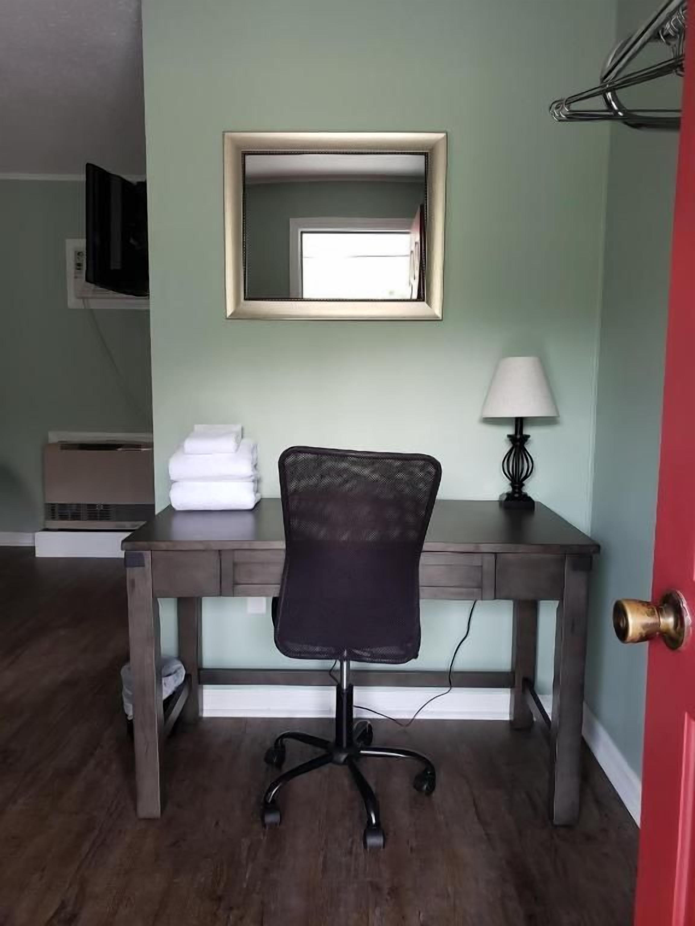 A room with a desk, chair, lamp, and a door.