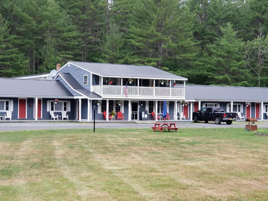 A two-story motel with a covered front porch, outdoor seating, and a flag.