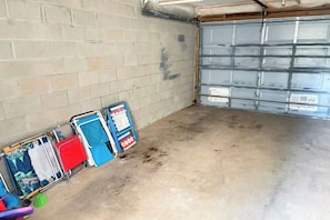 A garage with a concrete floor, a brick wall, and a closed garage door. - Bayfront Paradise! Lazy River, Beach Access & Private Patio! (Fort Walton Beach)