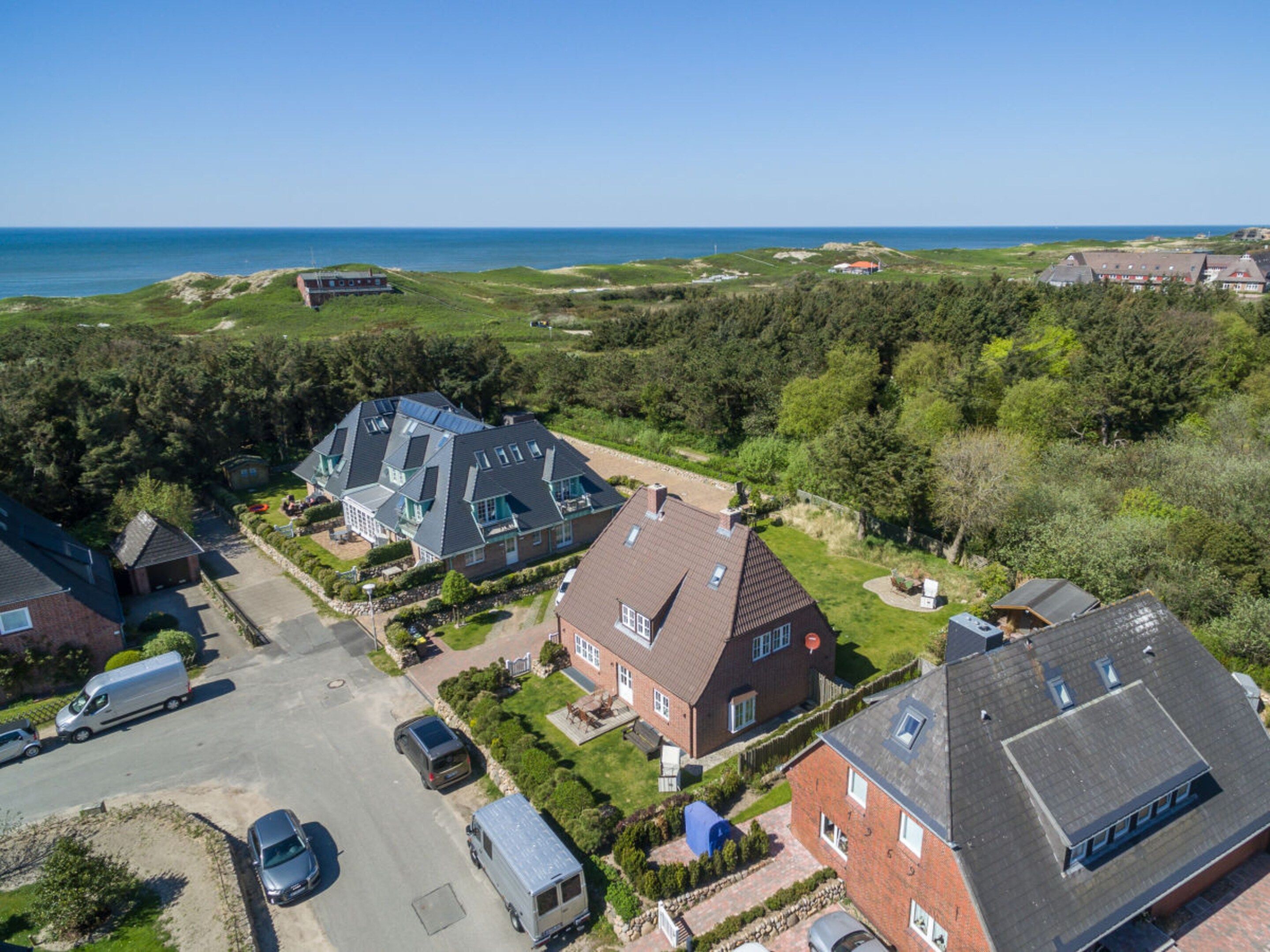 A residential area with houses, a parking lot, and a view of the sea.