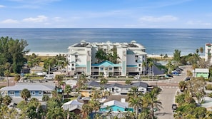 A beachfront hotel with multiple buildings, a parking area, and a view of the ocean. - Bright Beachfront Penthouse | Balcony Views + Pool (Treasure Island)