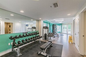 A gym with weightlifting equipment, exercise machines, and a mirrored wall. - Bright Beachfront Penthouse | Balcony Views + Pool (Treasure Island)