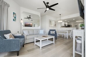 Un salon moderne comprenant un canapé, des fauteuils, une table basse et un coin repas avec une table et des chaises.