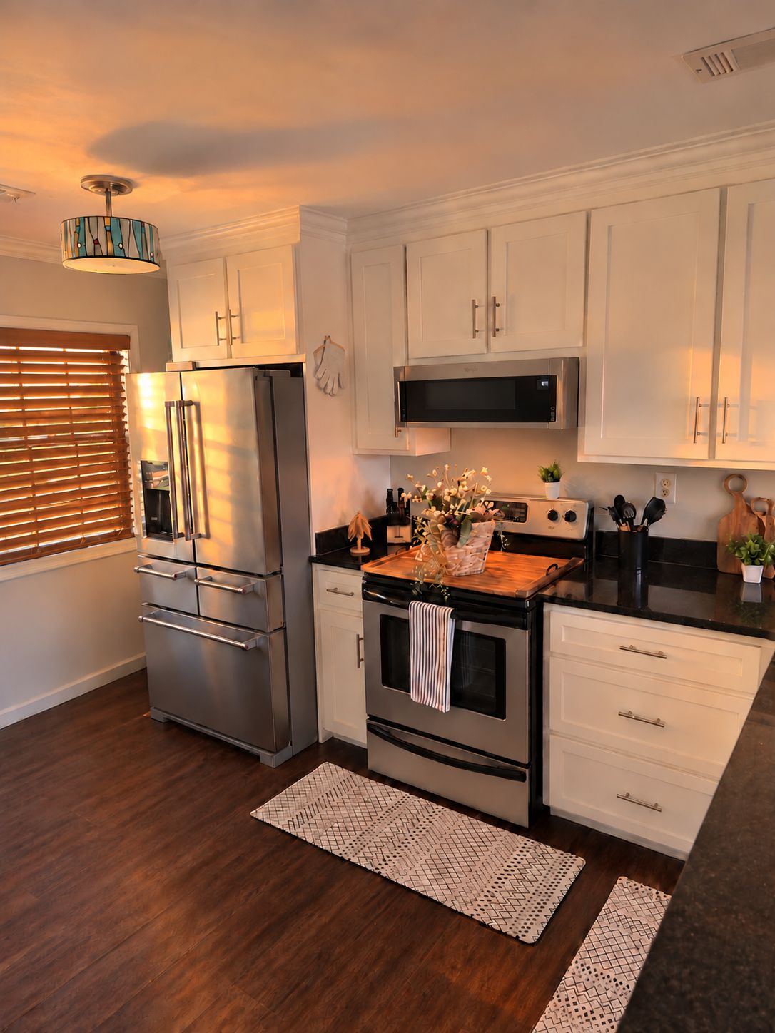 Una cocina moderna con electrodomésticos de acero inoxidable, armarios blancos y encimera de madera.