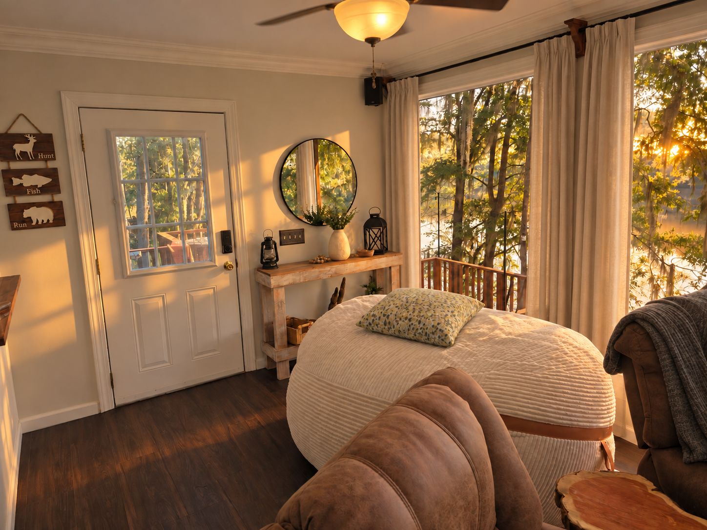 A bedroom with a bed, a wooden bench, a mirror, and a view of trees through the window.