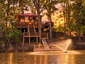 A wooden cabin with a red roof, surrounded by trees and a body of water. - Riverview w/Dock/Sleeps 4 (Uvalda)