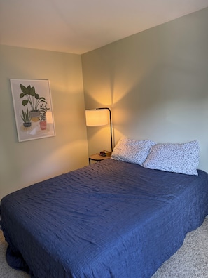 A bedroom with a bed, a nightstand, a lamp, and a wall-mounted plant. - Functional 3-bedroom apartment in delightful Montpelier perfect for families (Montpelier)