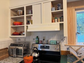 A kitchen with a built-in oven, a kettle, and various spices and cookware on shelves. - Functional 3-bedroom apartment in delightful Montpelier perfect for families (Montpelier)