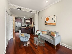 A modern living room with a grey sofa, a glass coffee table, and a bar stool. - Cozy Urban Studio | Fitness Hub | Perfect For 2 (Philadelphia)