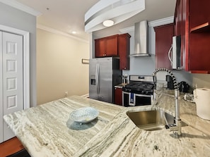 A kitchen with a marble countertop, stainless steel appliances, and wooden cabinets. - Cozy Urban Studio | Fitness Hub | Perfect For 2 (Philadelphia)