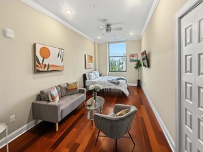 A modern bedroom with a bed, a sofa, a chair, and a small table. - Cozy Urban Studio | Fitness Hub | Perfect For 2 (Philadelphia)