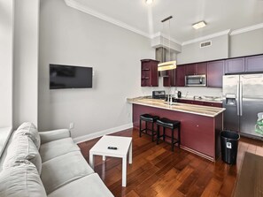 A modern kitchen with a central island, stainless steel appliances, and a flat-screen TV mounted on the wall. - Sleek City Flat 1BR | Culinary Hub | Ideal for 2 (Philadelphia)
