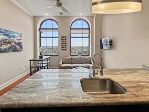A modern kitchen with a large island, a built-in sink, and a ceiling fan. - Sleek City Flat 1BR | Culinary Hub | Ideal for 2 (Philadelphia)