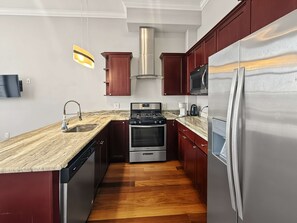 A modern kitchen with a stainless steel refrigerator, a built-in oven, a microwave, and a gas stove. - Sleek City Flat 1BR | Culinary Hub | Ideal for 2 (Philadelphia)