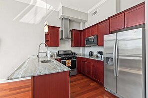 Una cocina moderna con una isla central, electrodomésticos de acero inoxidable y armarios color rojo.