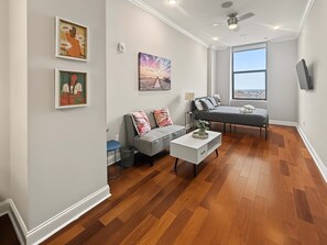 A modern living room with a sofa, a coffee table, and artwork on the walls. - Stylish City Escape | Comfy Studio Onsite Fitness (Philadelphia)