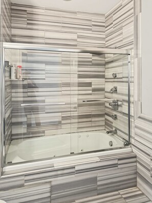 A modern bathroom with a glass-enclosed shower, marble-patterned walls, and a built-in vanity with a mirror. - Prime Studio City Hideaway | Gym Pass | Fits 2 (Philadelphia)