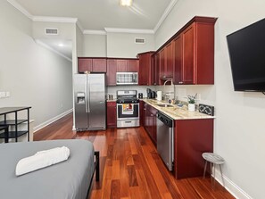 A compact kitchen with modern appliances, a dining area, and a bed. - Prime Studio City Hideaway | Gym Pass | Fits 2 (Philadelphia)