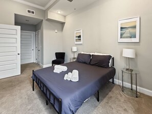 A hotel room with a large bed, a chair, a desk, and a picture on the wall. - Posh Urban 1BR | Gourmet District | Welcomes 2 (Philadelphia)