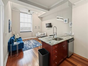 A modern kitchen with a marble countertop, a built-in dishwasher, and a window providing a view. - Posh Urban 1BR | Gourmet District | Welcomes 2 (Philadelphia)