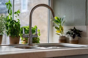 Ein Küchenspüle mit modernem Wasserhahn, umgeben von Topfpflanzen.
