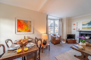 A living room with a dining table set for breakfast, a sofa, a fireplace, and artwork on the walls. - The Artist's Rooms | Central Chipping Norton - Pass the Keys (Chipping Norton)
