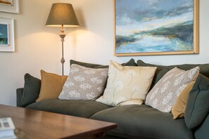 Ein Wohnzimmer mit einer Couch, einer Lampe und einem Gemälde an der Wand.
