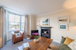 A living room with a fireplace, a sofa, a coffee table, and a bookshelf. - The Artist's Rooms | Central Chipping Norton - Pass the Keys (Chipping Norton)
