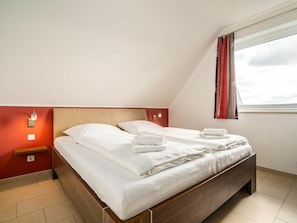 A single bed with white linens in a room with red walls and a window with curtains. - Lontargos Upper Floor Apartment (Goehren-Lebbin)