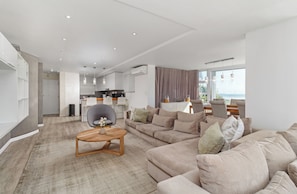 A modern living room with a sofa, a chair, and a coffee table. - Spacious Beachfront Retreat | Stunning Ocean Views (Cape Town)
