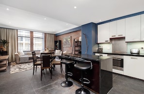 A modern kitchen with a central island, bar stools, and a dining area with a sofa and chairs. - Retro CBD Escape | Pool and City Living (Cape Town)