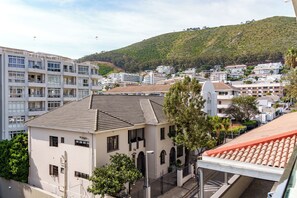 A coastal town with buildings, including a prominent white building with a tiled roof and arched windows. - The Sage | Central Sea Point Stay (Cape Town)