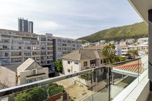 A residential area with multi-story buildings, a hill in the background, and a clear sky. - The Sage | Central Sea Point Stay (Cape Town)