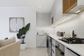 A modern kitchen with a built-in dishwasher, a gas stove, and a countertop with a toaster. - Luxe Modern Apartment | Ocean Views | Aircon (Umhlanga)