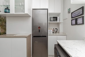 Una cocina moderna con un refrigerador de acero inoxidable, un microondas y una cafetera en la encimera.