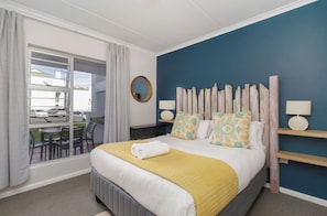 A hotel room with a bed, a view of the outside, a small table, and a chair. - Stylish 2 Bed Apartment | Big Bay Beach Club (Cape Town)