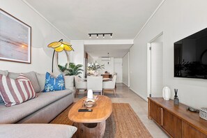Ein modernes Wohnzimmer mit einer Couch, einem Couchtisch und einem an der Wand befestigten Fernseher.