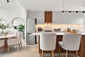 Une cuisine moderne dotée d’un îlot central, d’appareils électroménagers intégrés et d’un coin repas avec une table ronde et des chaises.