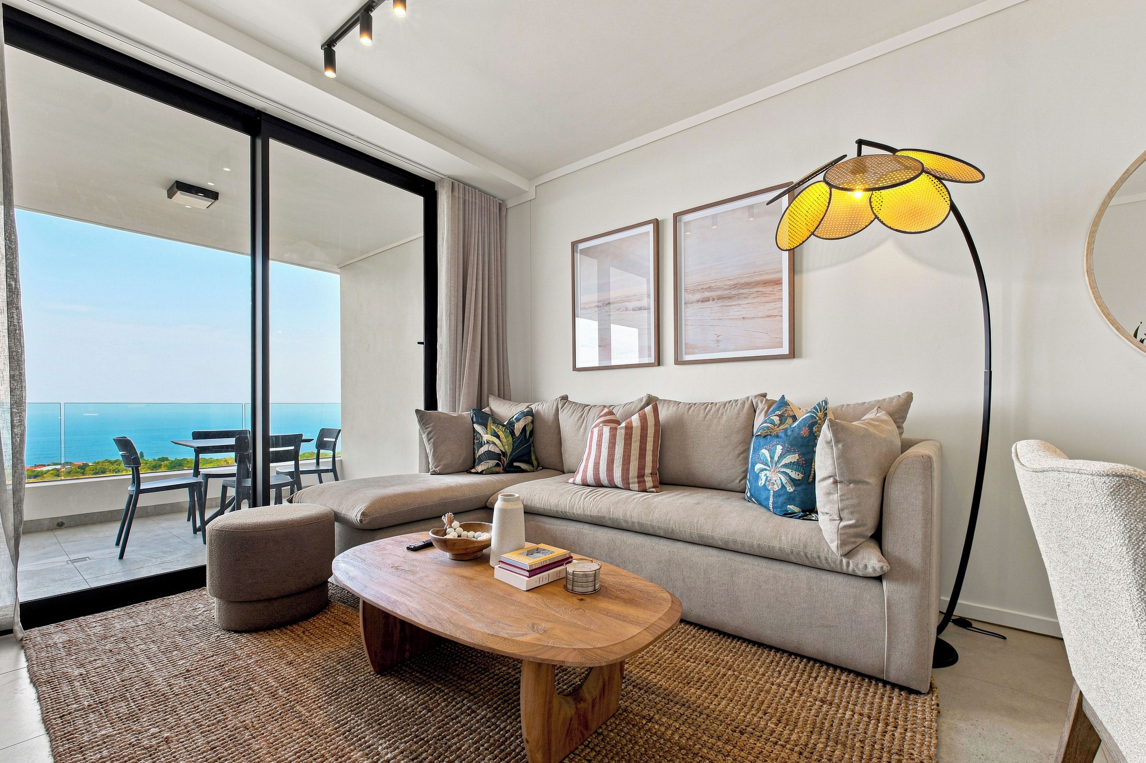 Een moderne woonkamer met een bank, salontafel en een groot raam met uitzicht op zee.