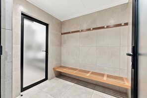 A modern bathroom with a glass door, a wooden bench, and a tiled floor. - Stylish Umhlanga 2Bed | Aircon and Gym (Umhlanga)