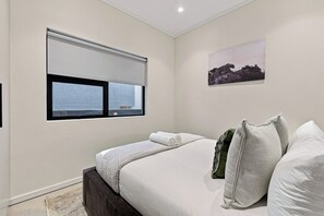 A bedroom with a large bed, a window with a view, and a picture on the wall. - Stylish Umhlanga 2Bed | Aircon and Gym (Umhlanga)
