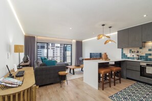 A modern apartment with a living area, kitchen, and dining space. - Elegant De Waterkant Stay | Pool and Gym (Cape Town)