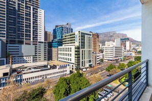 Une vue urbaine avec des bâtiments modernes, un ciel dégagé et une montagne en arrière-plan.