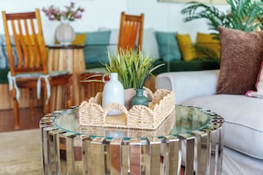 A round glass table with a woven tray, a white pitcher, and green plants. - Stylish Seaside Stay | Ocean Views and Balcony (Cape Town)