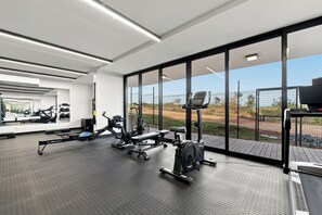 Ein modernes Fitnessstudio mit vielfältigen Trainingsgeräten, großen Fenstern und Blick ins Freie.