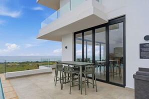 Eine moderne Terrassenanlage im Freien mit Tisch und Stühlen, mit Blick auf eine schöne Aussicht.