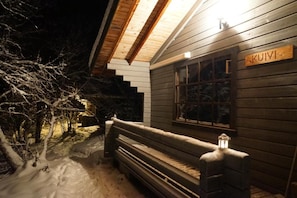 A wooden cabin with a bench outside, a window with a sign, and snow on the ground. - Muotkan Ruoktu Tunturikyla (Inari)